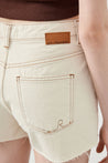 Close-up of Ruhe Ecru Denim Shorts by RA Denim, showcasing stitching detail and raw hem