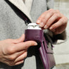 A woman using lnestudio's vegan AirPods Cover in dark purple vegan leather to protect her AirPods.