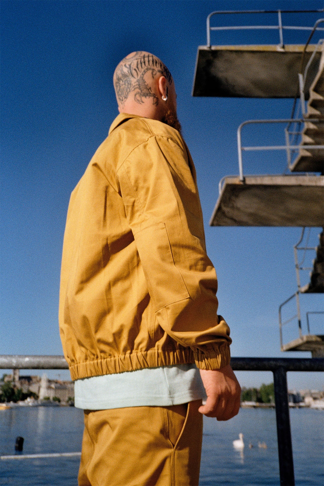 Man with tattoos sporting Mustard Yellow Patch Lightweight Men's Jacket, highlighting trendy elbow patches and comfortable elastic hem and cuffs.