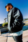 A man with a beard wearing the petrol blue patch jacket by French Menswear brand Crest