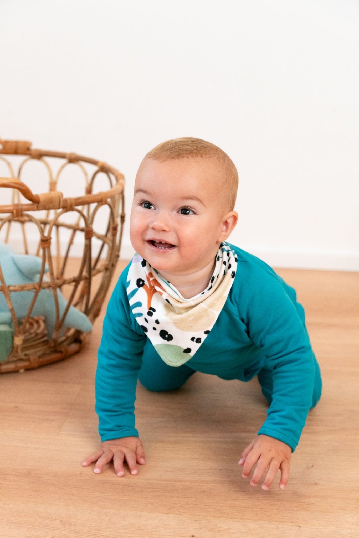 Ababy crawling on the floor with a bandana around his neck